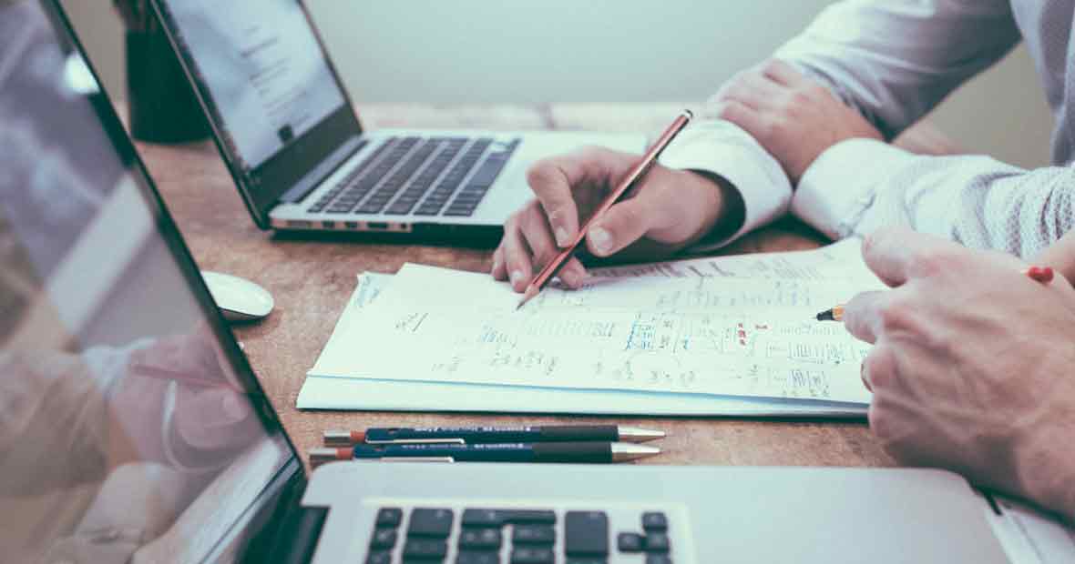 Deux professionnels discutant de graphiques avec des ordinateurs portables en arrière-plan.