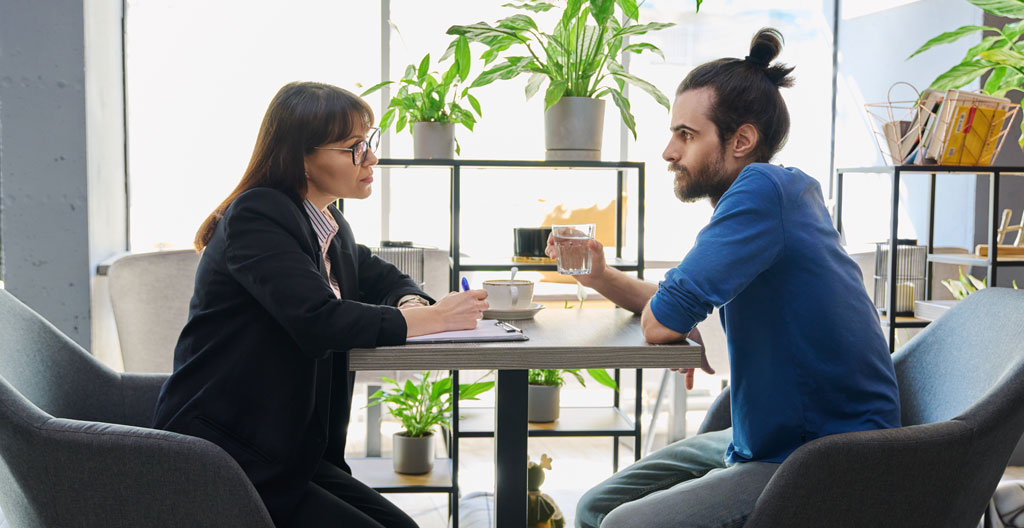 Conseiller professionnel et jeune candidat en interaction constructive lors d'une consultation emploi dans un bureau moderne à Lyon